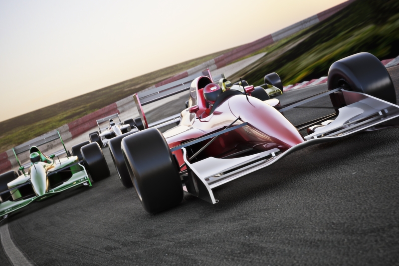 Red race car close up front view on a track leading the pack.