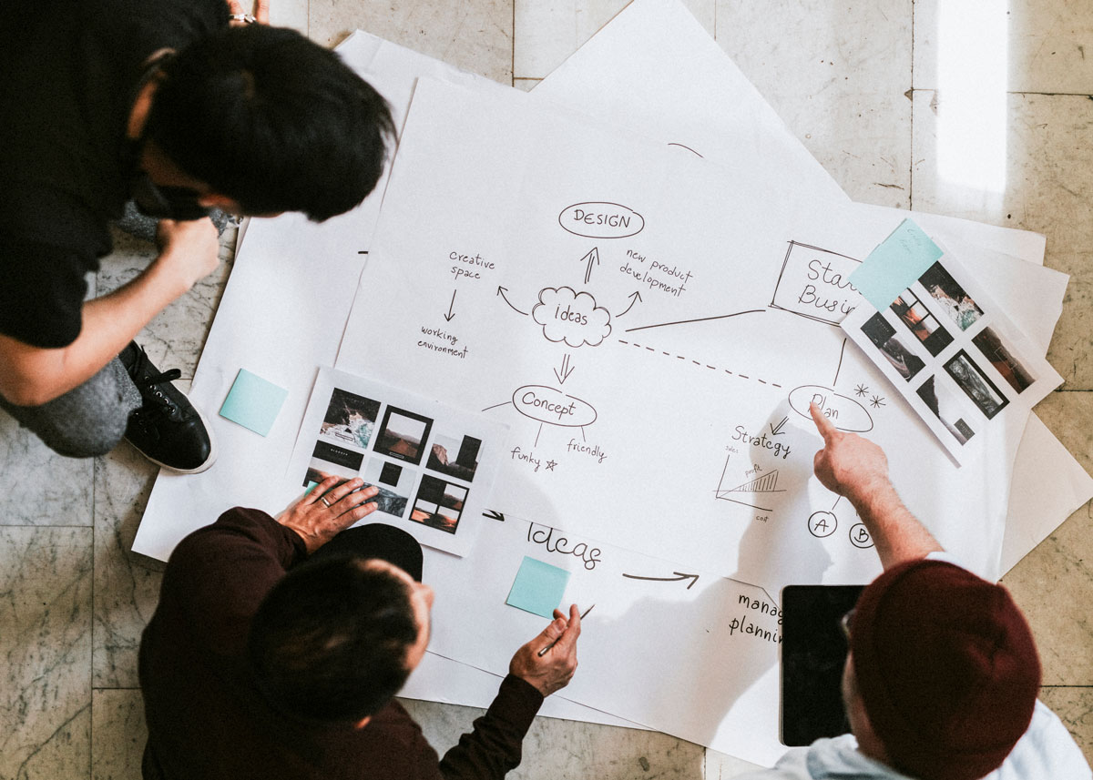 Three people work together on a diagram of their processes
